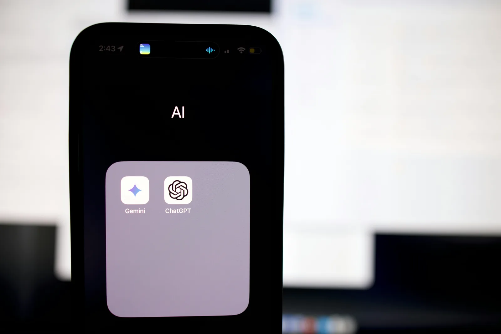 A smartphone screen showing a folder labeled “AI” with the Gemini and ChatGPT app icons.