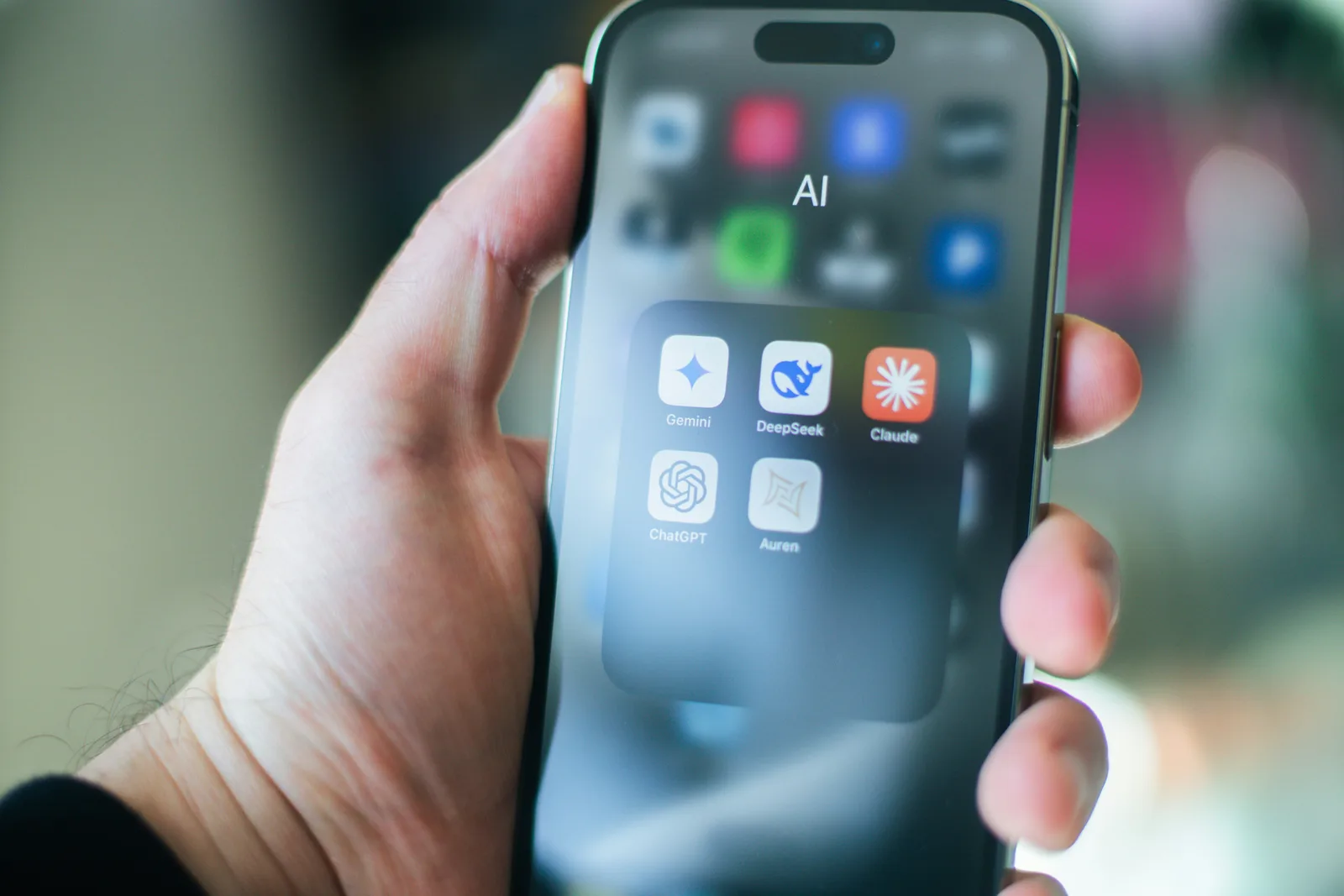 Person holding smartphone displaying AI tools like ChatGPT, Gemini, DeepSeek, and Claude, representing the evolution of AI SEO and search innovation.